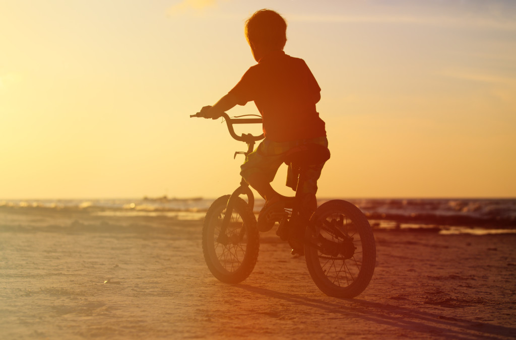 little boy riding bike at sunset beach