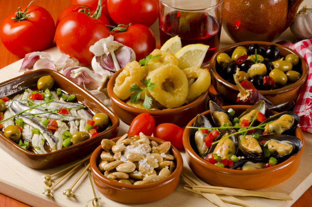Spanish cuisine. Assortment of Tapas including Serrano Ham, Marinated Olives, Mussels in Sauce and others, served with red wine.