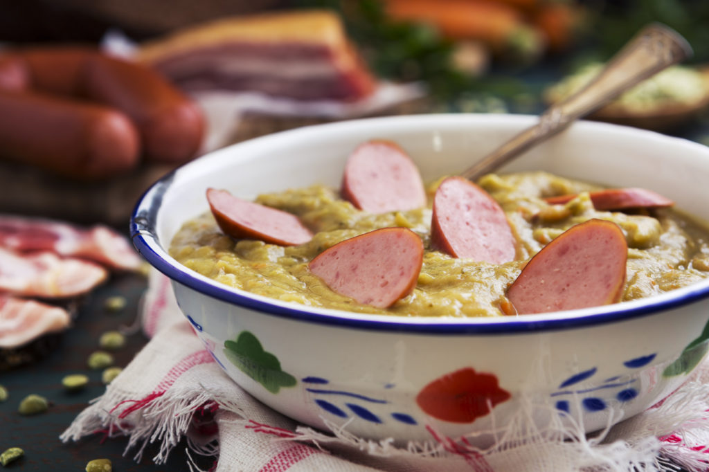 Traditional Dutch pea soup and ingredients on a rustic table
