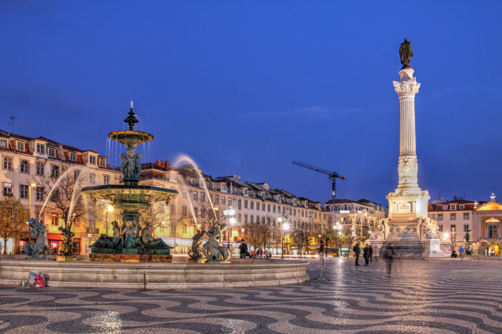 Night scene of Rossio Square, Lisbon, Portugal with one of its decorative fountains and column of Pedro IV.