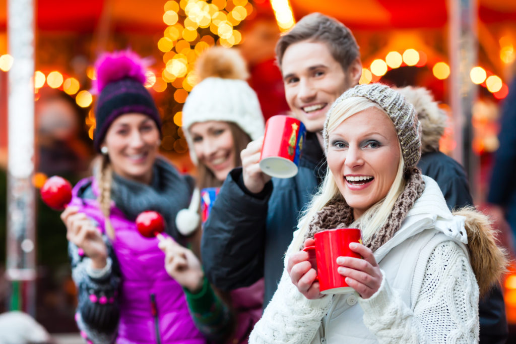 Friends drinking mulled wine and eating crystalized appels on German Christmas Market