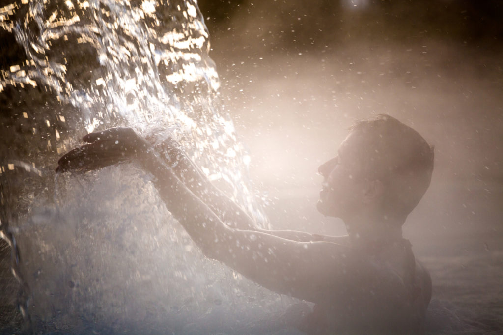 Happy young woman relaxing in thermal pool.