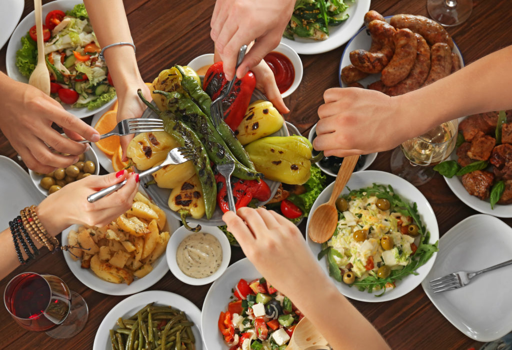 Friends passing plate with grilled peppers in restaurant