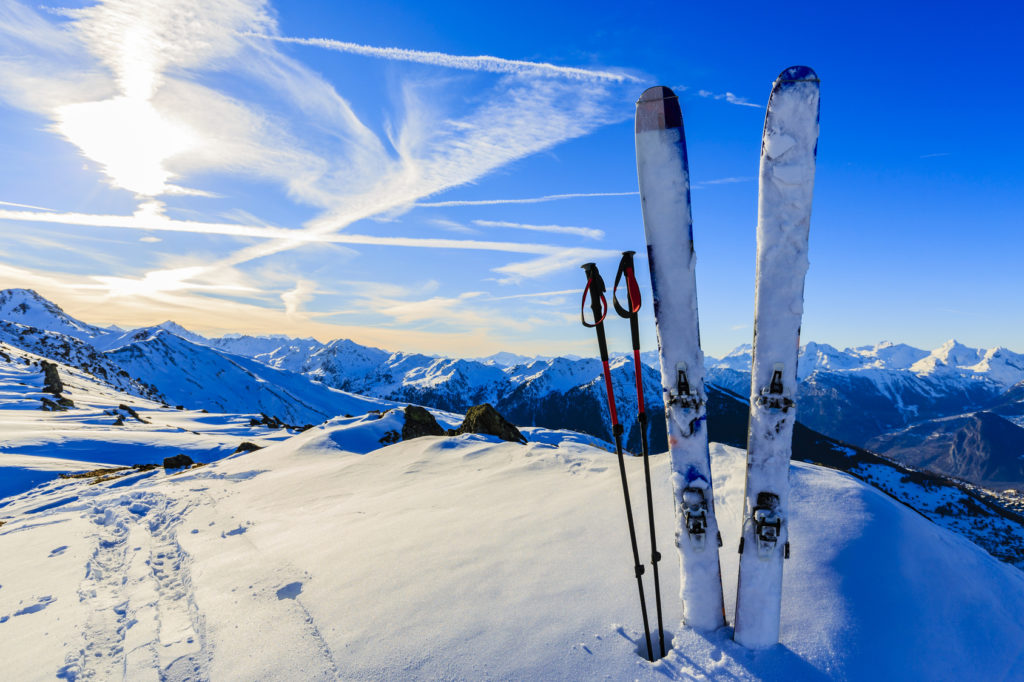 Ski in winter season, mountains and ski touring equipments on the top at sunrise.