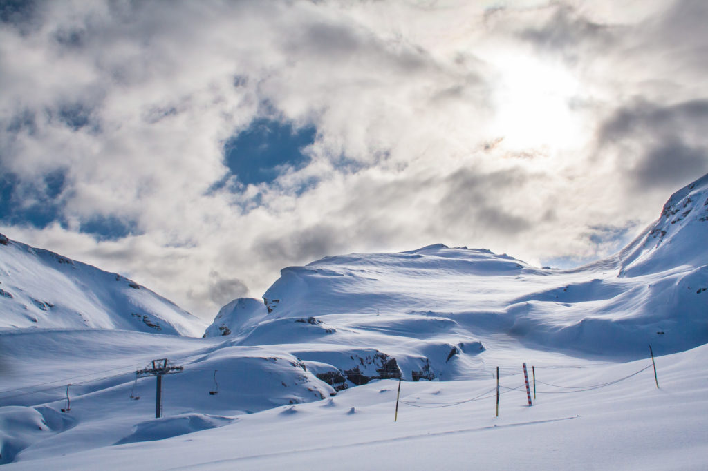 Snowy mountain with huge white cloud above and a ski lift in the foreground