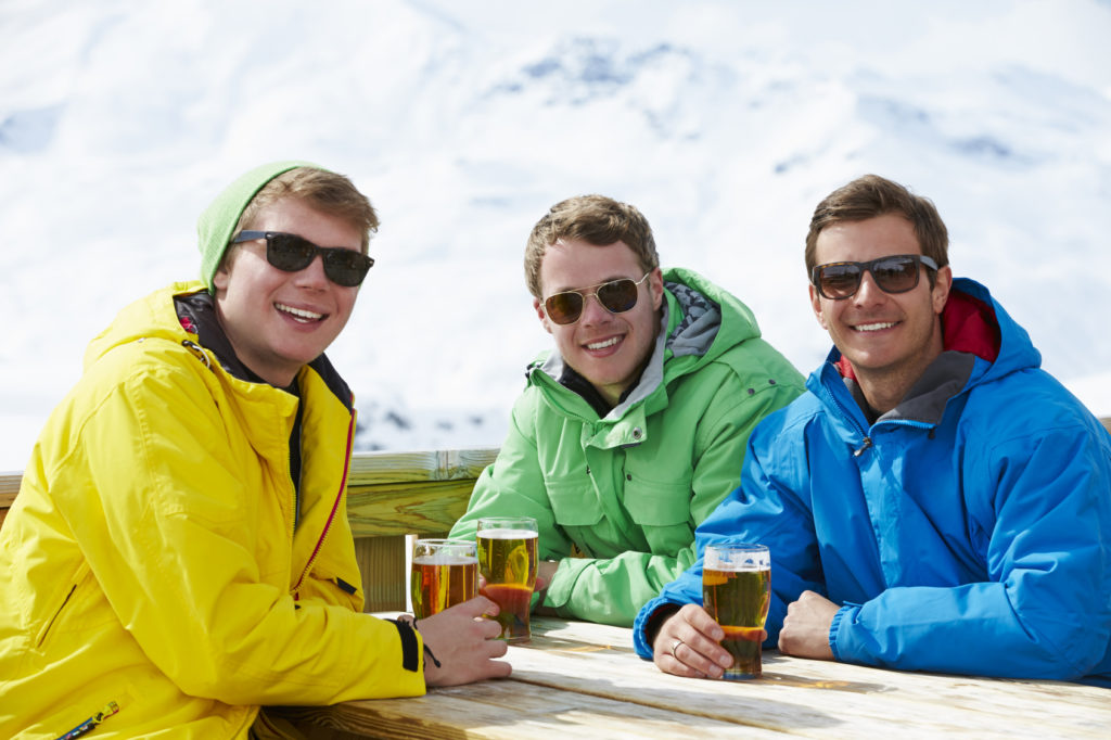 Group Of Young Men Enjoying Drink In Bar At Ski Resort