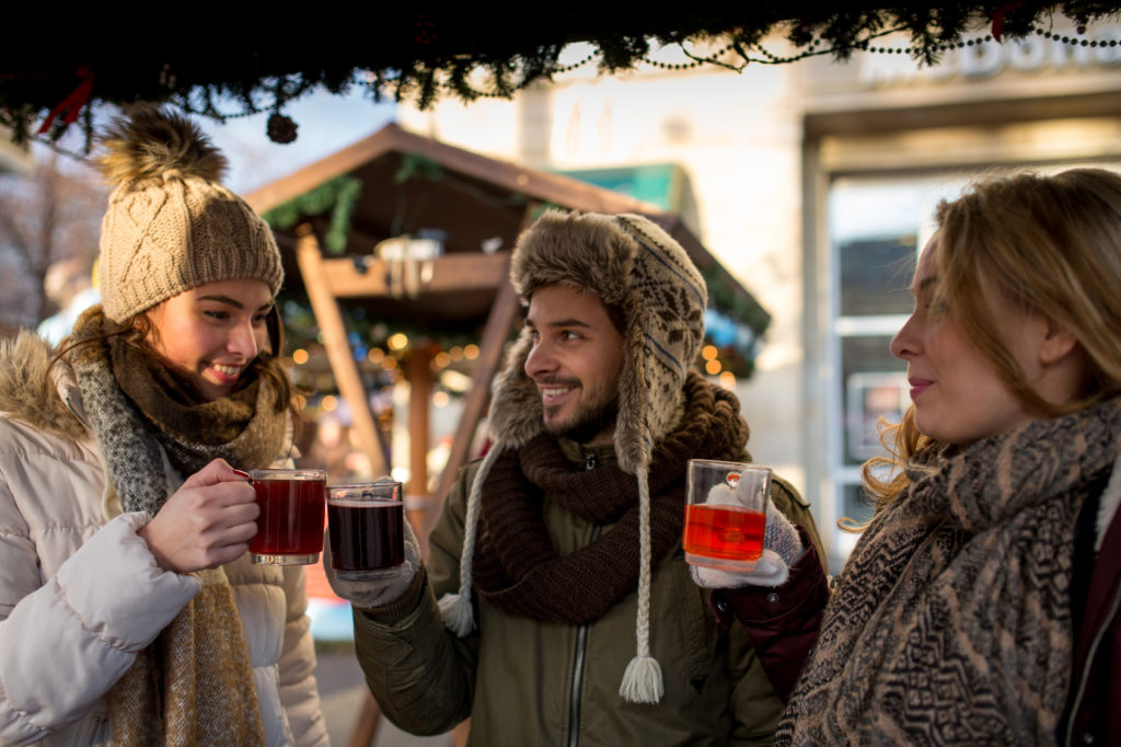 Couple and friend, Friends on a german Christmas market enjoying traditional mullet wine and talk to each other