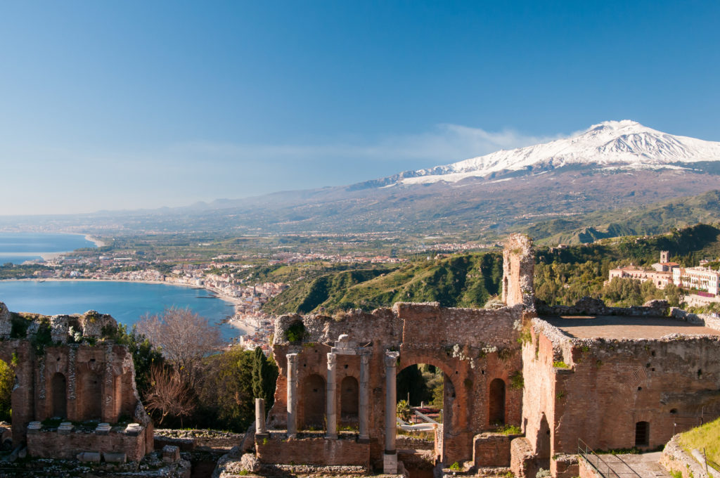 View of some columns in the stage of the greek theater in Taormina and a perspective of snowy mount Etna