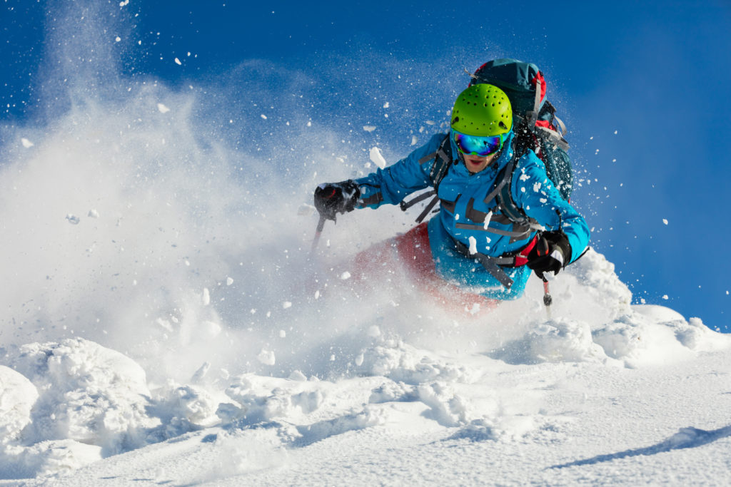Freeride skier running downhill in freeze motion of snow powder.