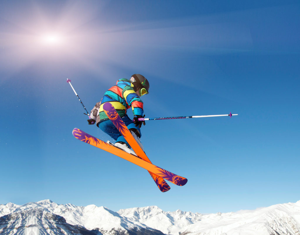 Skifahrer springt vor blauem Himmel und Sonne