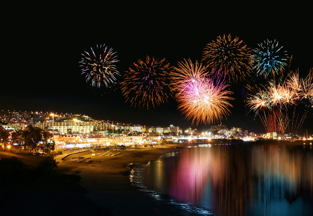 Water reflecting night fireworks in seashore holiday resort festive
