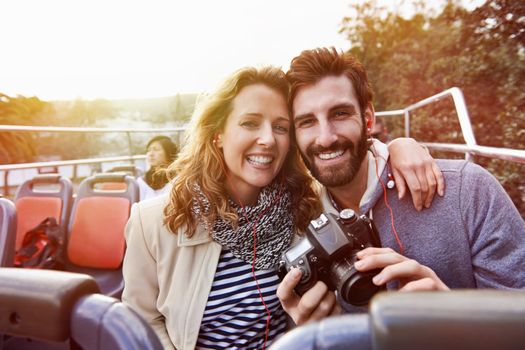 portrait of couple enjoying holiday vacation sightseeing bus open top tour